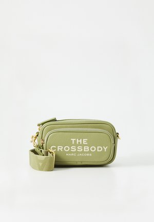 Groene crossbody tas van textuurmateriaal, met gouden hardware en gedurfde witte letters, ontworpen met een compacte, rechthoekige vorm.