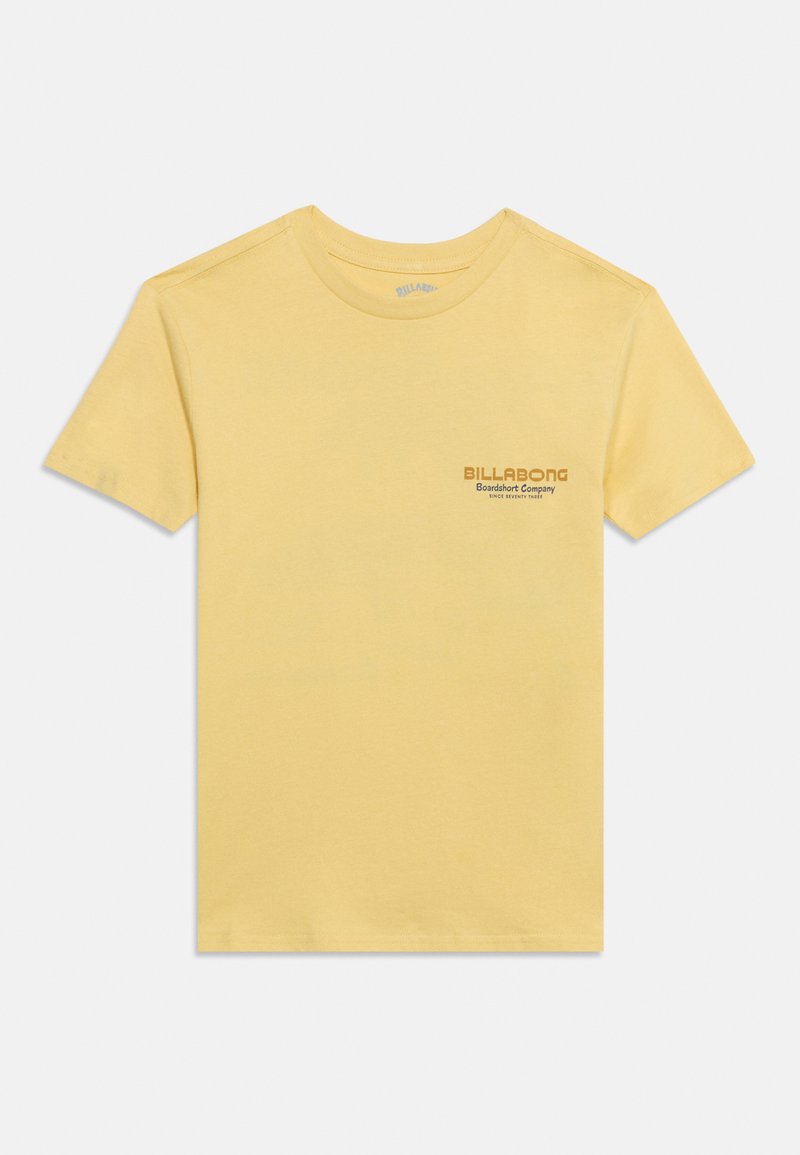 T-shirt jaune à manches courtes et col rond avec un petit texte « Billabong Boardshort Company » imprimé sur le côté gauche de la poitrine.