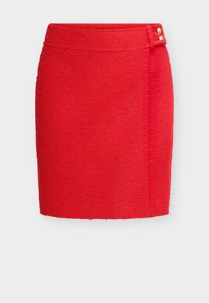 Gonna corta rossa dalla texture strutturata, con taglio dritto, vita alta e due piccoli bottoni dorati sul fianco della cintura.