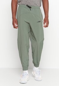 Lekka, oliwkowozielona dresowa spodnie z elastycznymi ściągaczami, sznurkiem w pasie i funkcjonalnymi kieszeniami. Z logo na udzie.
