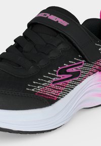 Μαύρο sneaker Skechers με ροζ και λευκές λεπτομέρειες, ροζ λογότυπο, μαύρα κορδόνια και λουράκι βέλκρο στο πάνω μέρος για δέσιμο.