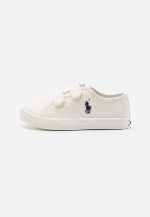 Sneaker bianco in tela con due cinturini in Velcro, suola in gomma e logo blu di un giocatore di polo sul lato. Texture liscia e forma arrotondata.