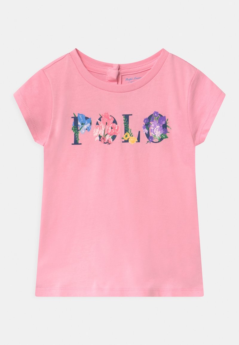 Camisa rosa de manga corta para niño pequeño con texto floral "Polo" en el pecho y un pequeño ojal con botón en la parte posterior del cuello.