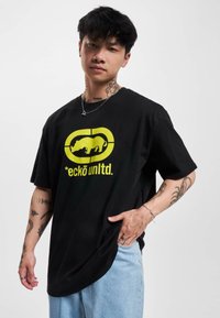Juodas medvilninis marškinėliai su dideliu geltonu bivolo logotipu ir užrašu "*ecko unltd." priekyje. Trumpomis rankovėmis ir laisvu siluetu.