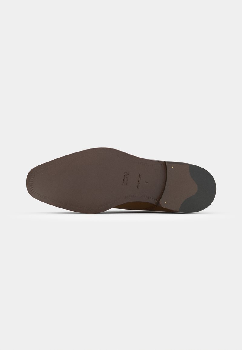 Semelle en cuir marron avec une finition lisse, bout arrondi et couture décorative. Présente un accent en caoutchouc plus foncé au niveau du talon.