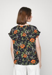 Camisa preta com estampado floral em padrões laranja e verde, com mangas curtas franzidas, corte solto e gola redonda. Ideal para uso casual.