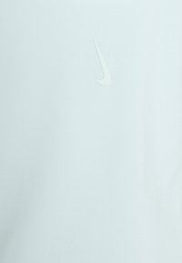Camisa de manga corta azul claro hecha de una tela suave, con un sutil logo blanco de Nike en la parte frontal. Textura suave, diseño minimalista.