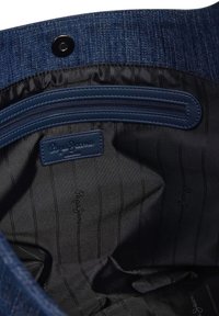Denim interieur van een tas met een marineblauwe ritszak; donkere stof met subtiele strepen en geperste "Pepe Jeans" branding.