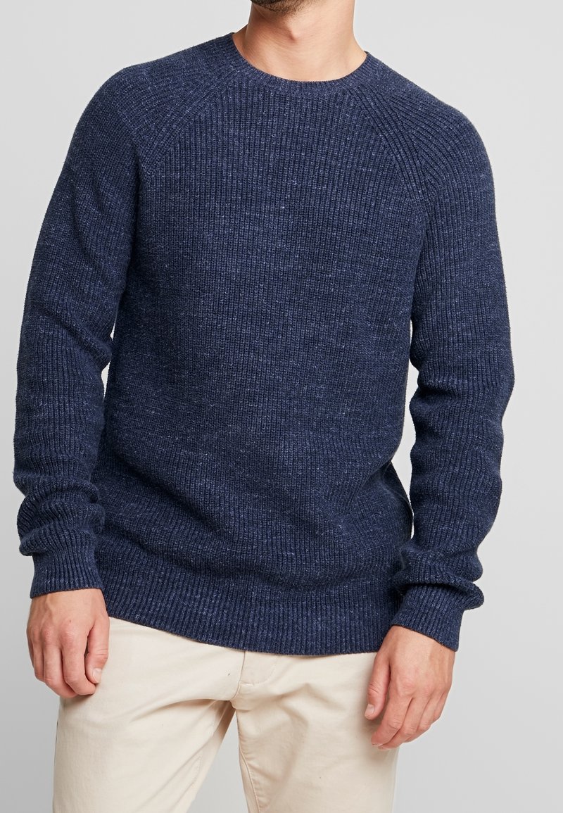 Marineblauer gestrickter Pullover mit geripptem Muster, Rundhalsausschnitt und langen Ärmeln. Verfügt über eine lockere Passform und ein Raglan-Ärmel-Design.