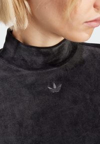 Sort højhalset pullover lavet af blødt stof med tekstureret finish. Har et lille, afdæmpet broderet logo på brystet.