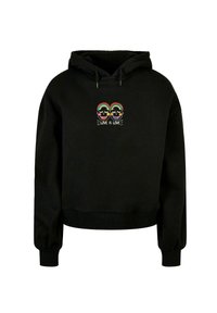 Black cropped hoodie made of soft fabric. Features a colorful graphic of two smiling faces and the text “LOVE IS LOVE” on the front.