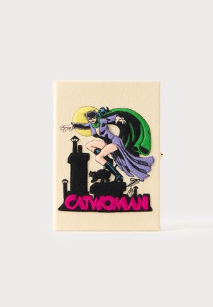Catwoman i lilla dragt og grøn kappe kryber sammen på toppen af en sort tag-silhuet med en sort kat og en lys gul måne bag sig.