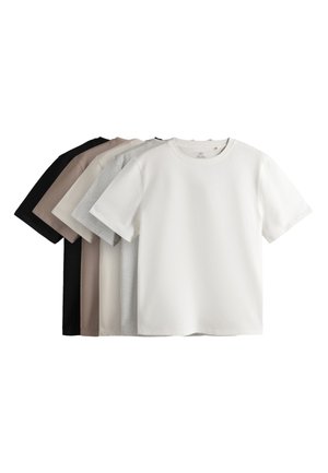 Kvinde iført sorte bukser med vide ben med side striber, sort kortærmet top, sorte sko, solbriller og gyldne armbånd på en ensfarvet baggrund.