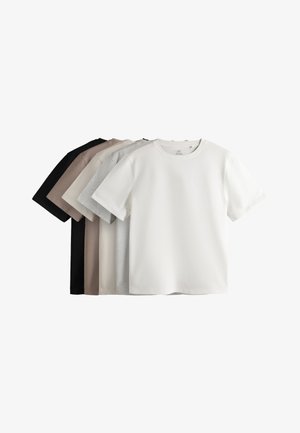 Kvinde iført sorte bukser med vide ben med side striber, sort kortærmet top, sorte sko, solbriller og gyldne armbånd på en ensfarvet baggrund.