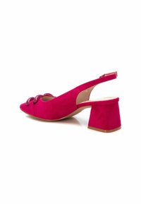 Zapato de tacón tipo slingback en ante rosa con punta afilada, que presenta tres acentos redondeados en la parte superior y un tacón grueso. Su diseño simplista resalta la textura.