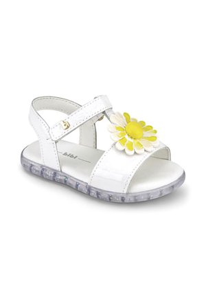Biała sandałka dla malucha z paskiem na rzep, żółto-białą dekoracją stokrotki z przodu oraz przezroczystą podeszwą z błyszczącymi elementami.