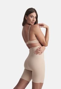 Shorts modeladores beige con cintura alta y diseño alisador. Fabricados en material elástico, con costuras simples y hardware mínimo.