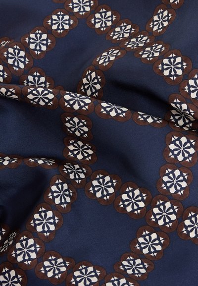 Tengerészkék szövet barna és fehér virágmintás négyzetek geometriai mintájával, amelyek kereszteződő láncokba rendezve vannak.