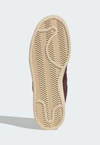 Brown sneaker sole with textured beige rubber. Features zigzag tread for traction and smooth edges, designed for durability.