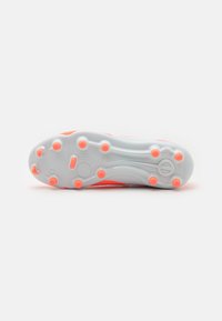 Crampon de football avec une semelle extérieure blanche et des accents orange vif, présentant des crampons ronds pour l'adhérence et une semelle texturée pour un meilleur grip.