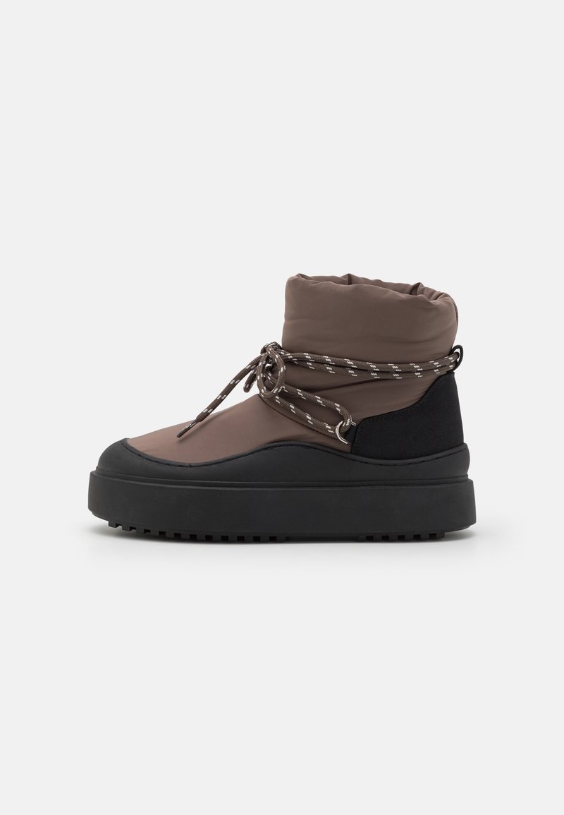 Bottine marron matelassée avec semelle et talon noirs, lacets enroulés attachés autour de la cheville pour la fermeture et le style.
