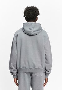 Gray hooded sweatshirt with a relaxed fit, ribbed cuffs, and hem. Made from soft material with a clean, minimalistic design.