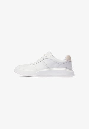 Zapatilla de cuero blanca con superficie lisa, puntera redondeada, detalles perforados y un suave acento de gamuza beige en el talón. Suela de goma plana.
