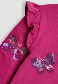 Garbote rosa con scollo arricciato e due design di farfalle ricamate in paillettes, che evidenziano motivi e texture colorate.