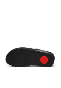 Zwarte rubberen zool met een gestructureerde grip, voorzien van een ronde rode accent en het reliëfmerk "fitflop." Gladde, platte ontwerpen.