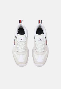 Sneaker bianchi con dettagli in mesh e pelle, dotati di una suola spessa e design con lacci. Logo di Tommy Hilfiger sulla linguetta e sul lato.
