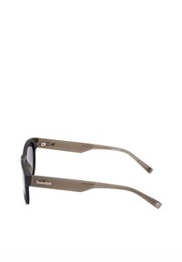 Sluneční brýle Timberland s černým rámečkem a hnědými polo-transparentními nohami. Vybavené rovnými stranami a detaily loga na boku.
