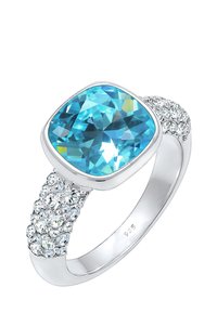 Sterling sølv ring med en stor, cushion-cut blå sten og flere små klare sten på ringen, hvilket skaber et struktureret udseende.