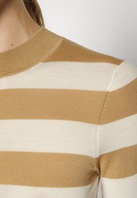 Gestreiftes Strickoberteil in Beige und Hellbraun. Mit einem gerippten Rundhalsausschnitt und glatter Textur. Sichtbare Nähte an der Schulter und an der Seite.