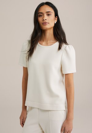 Vit, kortärmad topp med rund halsringning, tillverkad av ett slätt tyg; har puffärmar och rak skärning med sidoflikar.