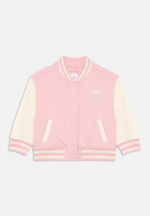 Giacca varsity rosa con maniche crema, colletto a costine e polsini a righe. Presenta bottoni a pressione e un dettaglio logo argento discreto. Texture liscia.
