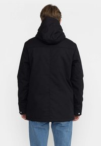 Giacca nera con cappuccio realizzata in tessuto intrecciato, caratterizzata da un taglio dritto, cuciture a vista e bottoni a pressione sui polsi.