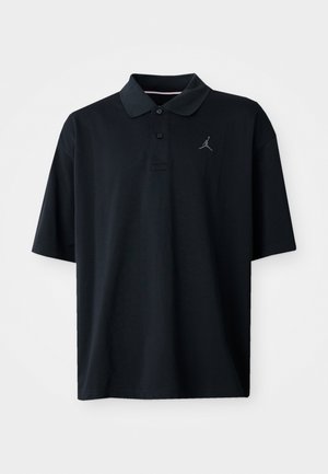 Polo noir en tissu lisse, avec un col, des manches courtes et un petit logo Jordan gris brodé sur la poitrine gauche.