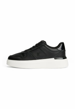 Black low-top sneaker with stitched details, lace-up front, white thick sole, and a small embossed logo on the side panel.