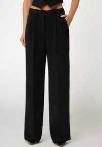 Pantaloni neri a gamba larga con vita alta, fronte plissettato, tasche laterali e texture liscia. Vestibilità su misura con un design pulito.