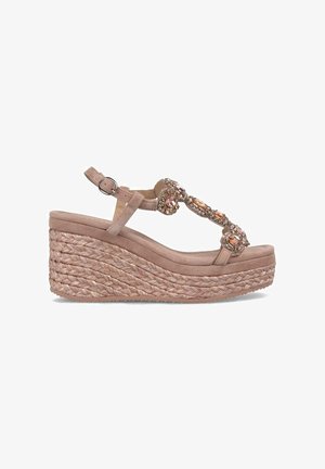 Sandale à semelle compensée en daim beige doux, avec une plateforme en jute tissée, des accents en pierre décoratifs et une sangle de cheville ajustable.