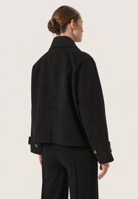 Zwarte cropped jas van wol, met een uitgesneden kraag, knoopsluiting bij de mouwen en een gladde textuur, ontworpen voor een getailleerde uitstraling.