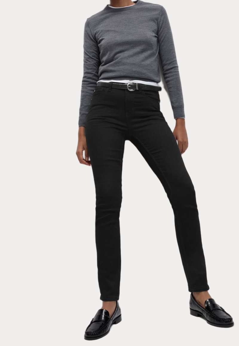 Svarta smala jeans i kombination med en grå långärmad skjorta. Outfitsen kompletteras av svarta loafers. Slät tyg, åtsittande design.