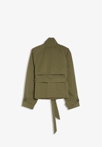 Giacca corta verde oliva con maniche lunghe, cintura annodata in vita e dettagli a fascia sui polsini, vista da dietro.