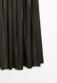 Černá saténová sukně s volným designem, nařasená v pase, s hladkou, lesklou texturou a lemem, který jemně splývá.