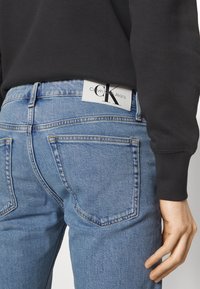 Bleka blå denim jeans med en något avsmalnande passform, med bakfickor och en Calvin Klein Jeans-logotyp på midjebandet.