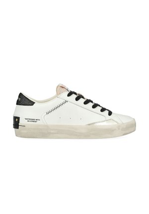 Sneaker in pelle bianca con lacci neri, dettagli metallici argentati e una robusta cappe nera testurizzata. Presenta cuciture decorative e testo stampato.