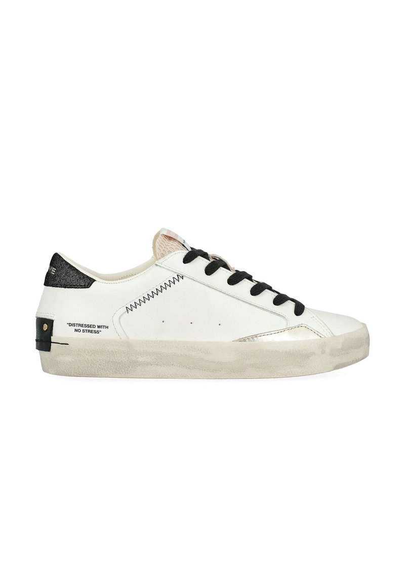 Baskets en cuir blanc avec des lacets noirs, des accents argent métallisé et un capuchon de talon noir texturé. Présente des coutures décoratives et un texte imprimé.