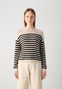 Stripet genser i beige og svart, strikket tekstur, vid hals, lange ermer, ribbestrikkede mansjetter og hem, kombinert med lyse bukser.