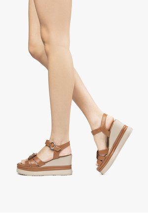 Brown wedge sandals with a textured strap design, buckle detail, and a beige platform sole. Open-toe style showcases feet.