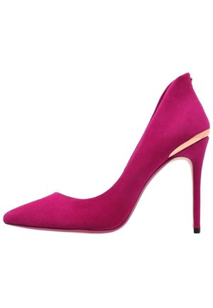 Fuchsia suède pump met een spits toelopende neus en een hoge naaldhak, voorzien van een metalen accent op de hak. Overal een gladde textuur.